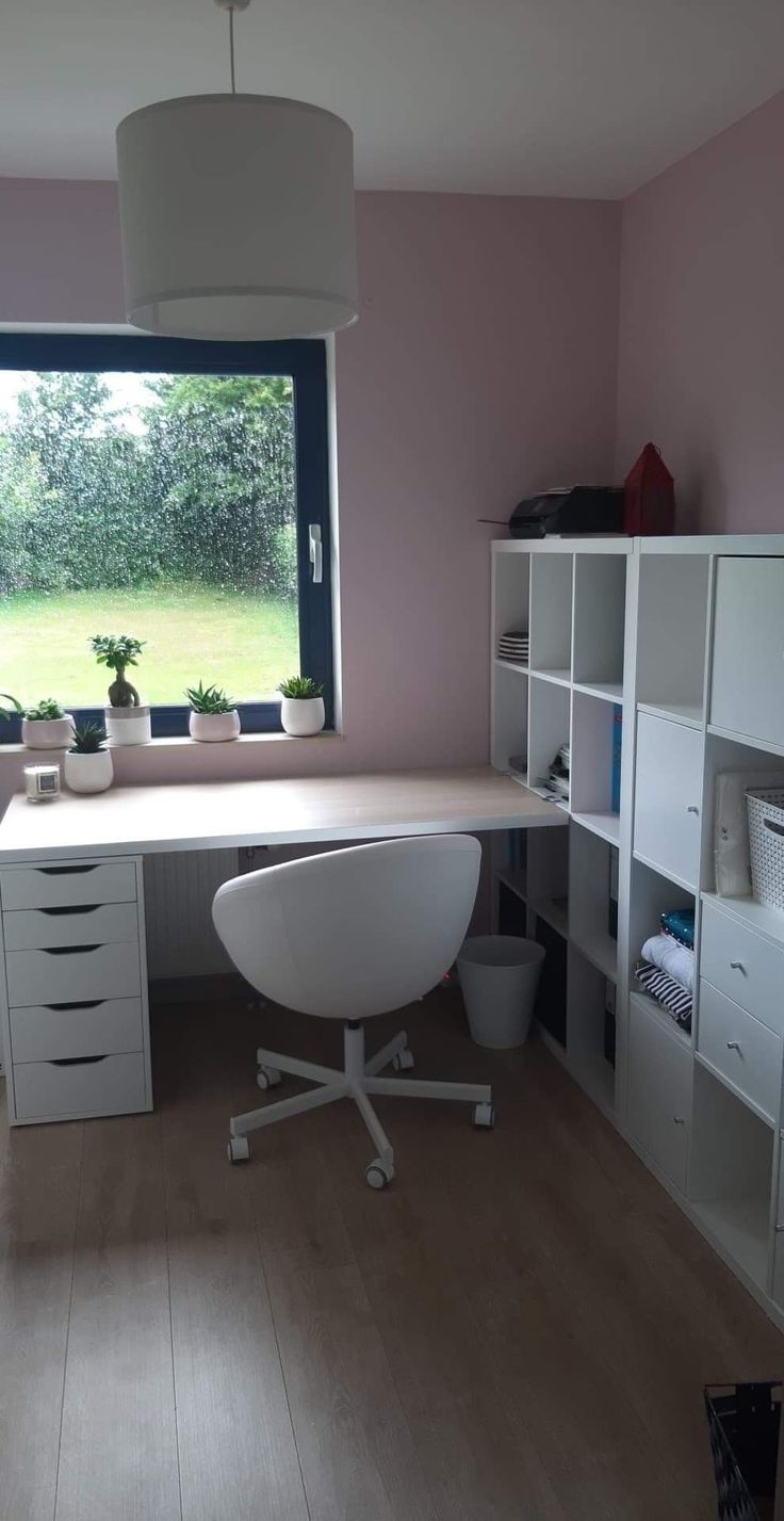 a room with a desk, chair and shelves in front of a large window that looks out onto a grassy field