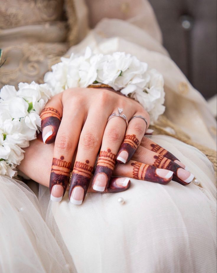 a woman's hands with hennap and flowers on her wedding day,