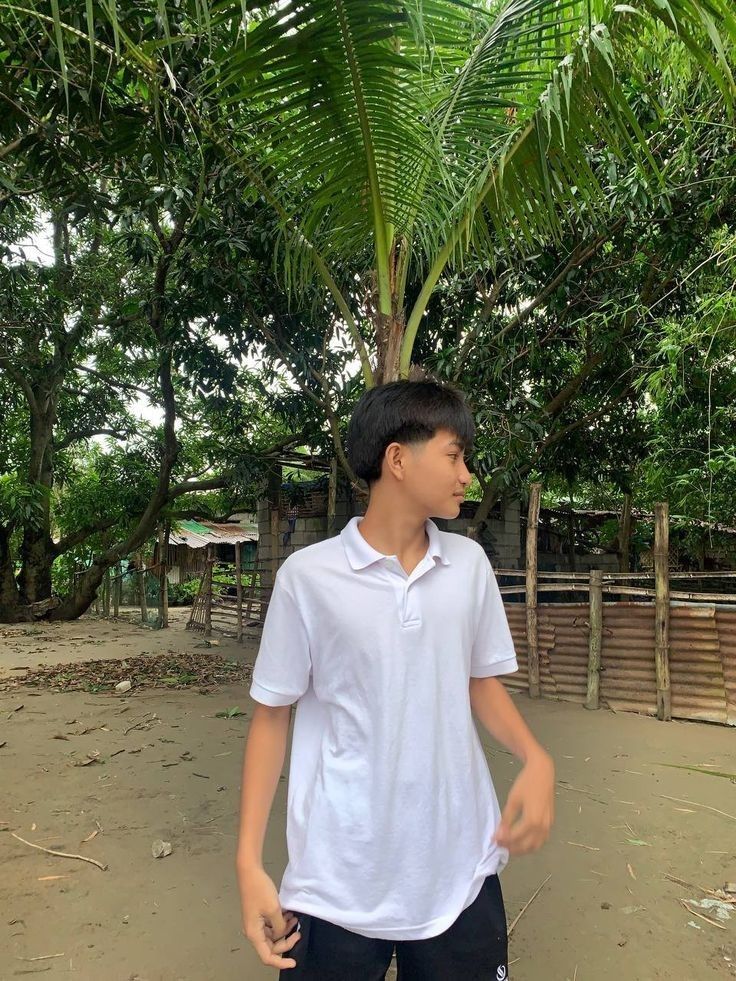 a young man standing in front of a palm tree