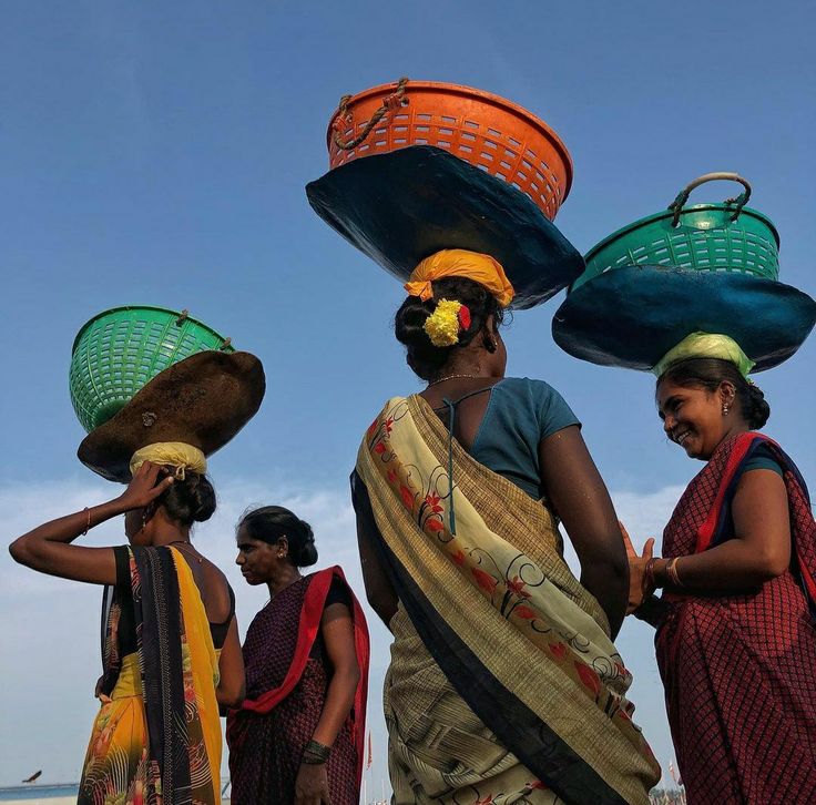 three women are carrying baskets on their heads