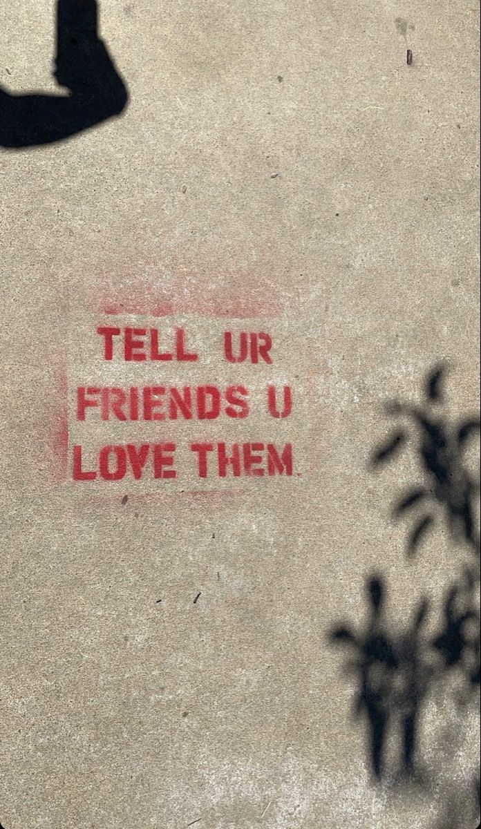 the words tell us friends u love them written in red ink on a concrete surface