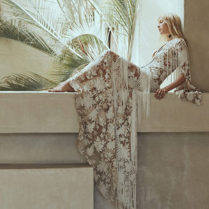 a woman sitting on the ledge of a window sill in front of a palm tree