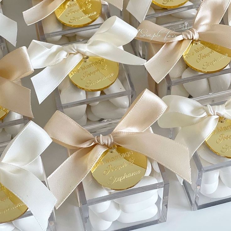 several small boxes filled with white and gold cookies covered in ribbon bowknots