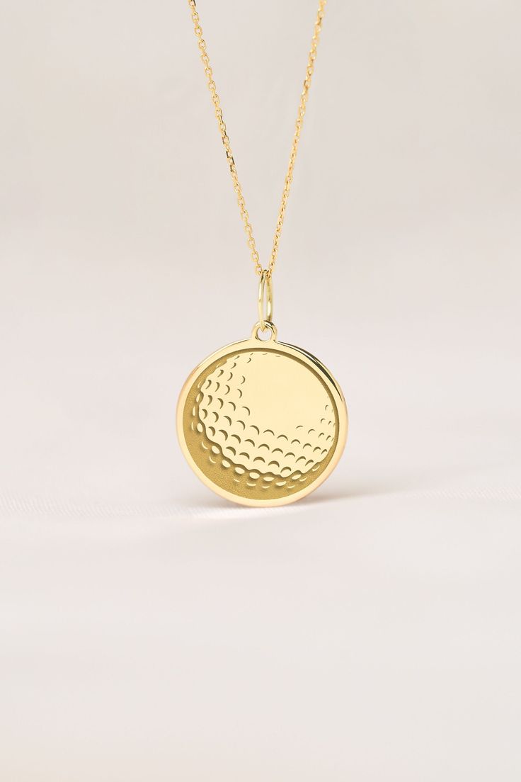 a gold necklace with a golf ball on it