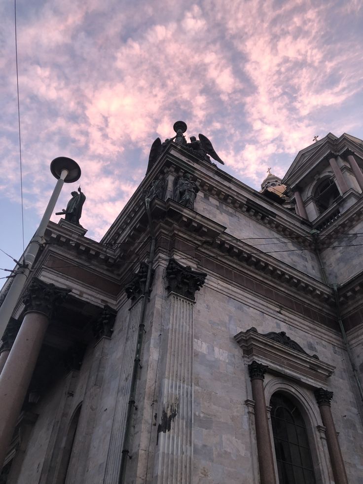 an old building with statues on the top and sky in the background