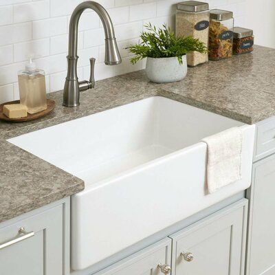 a white kitchen sink sitting under a faucet next to a counter with soap