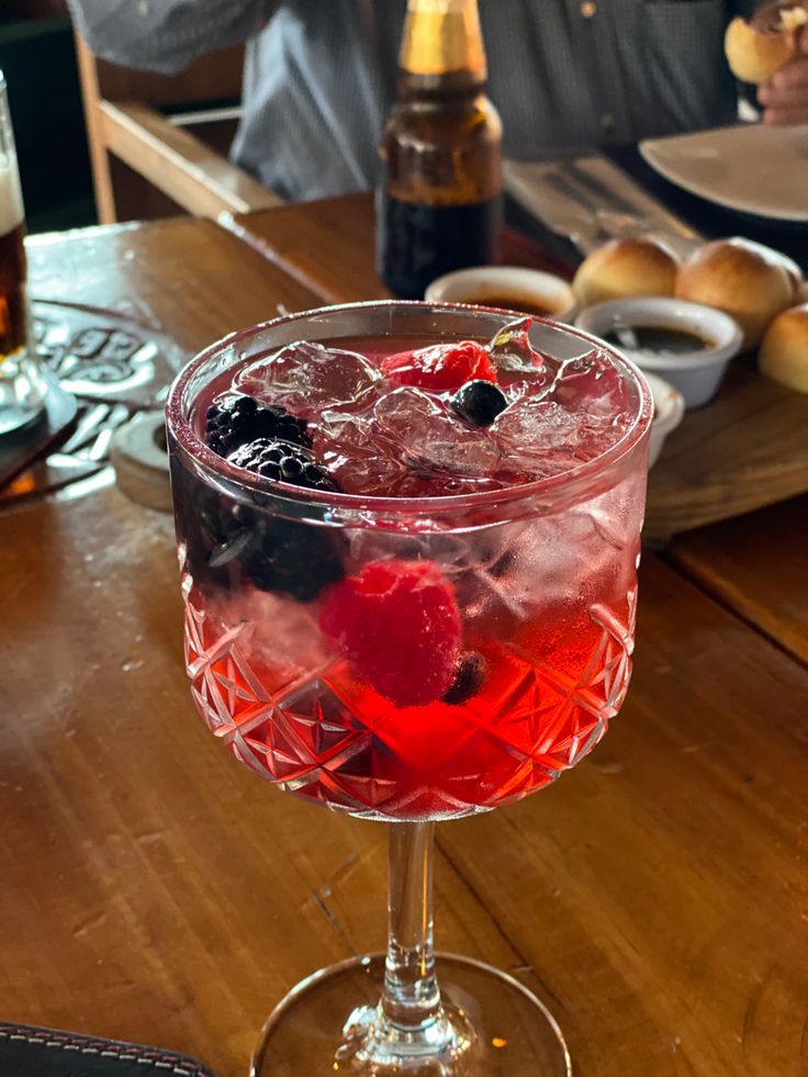 a close up of a wine glass on a table with food and drinks in the background