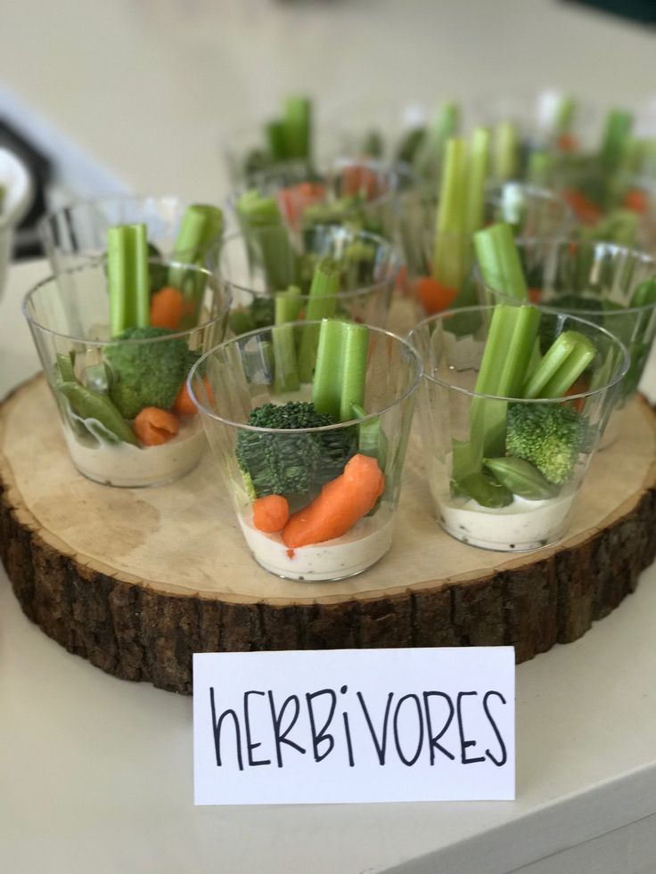 small cups filled with veggies on top of a wooden tray next to a sign that says herb vores