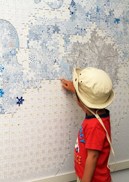 a little boy pointing at a wall with blue and white designs on it