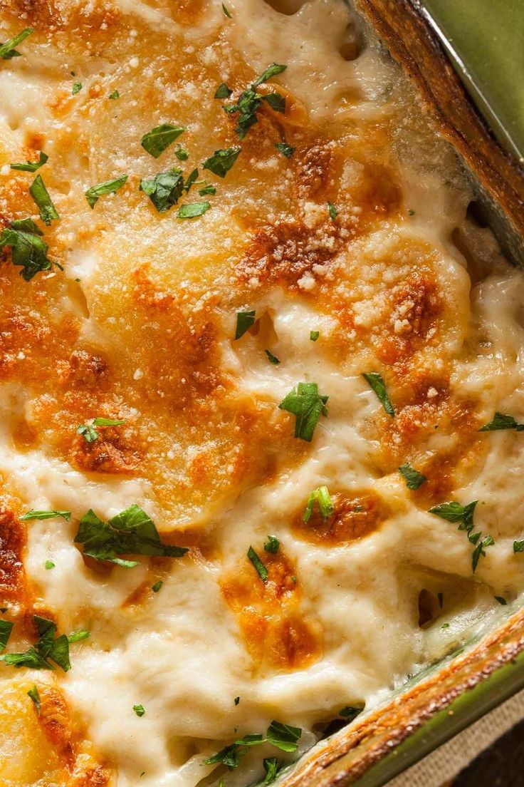 a casserole dish with cheese and parmesan on the top, garnished with fresh herbs