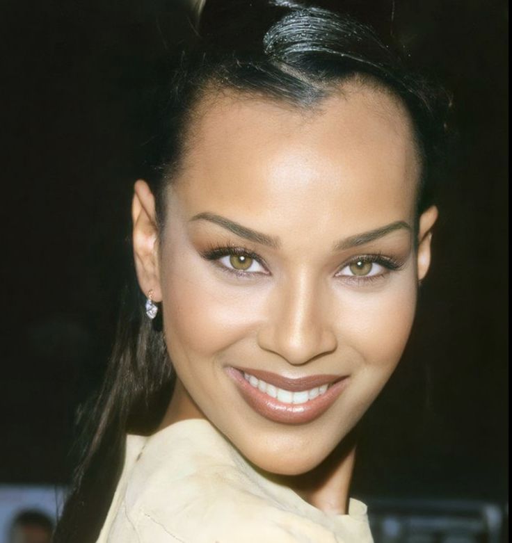 a close up of a person with a smile on her face and hair in a ponytail