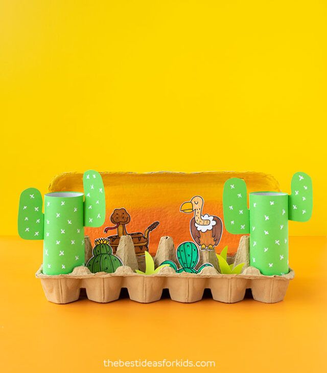 a toy train with cartoon characters on the track and cactuses in the sand, against a bright yellow background