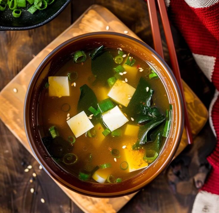 a bowl of soup with tofu and green onions