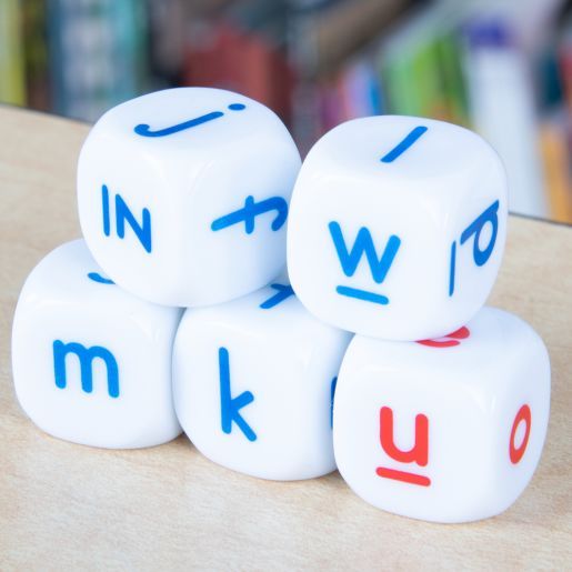 three white dices with red and blue letters sitting on top of each other in front of bookshelves