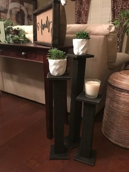 three planters are sitting on the floor in front of a mirror and table with candles