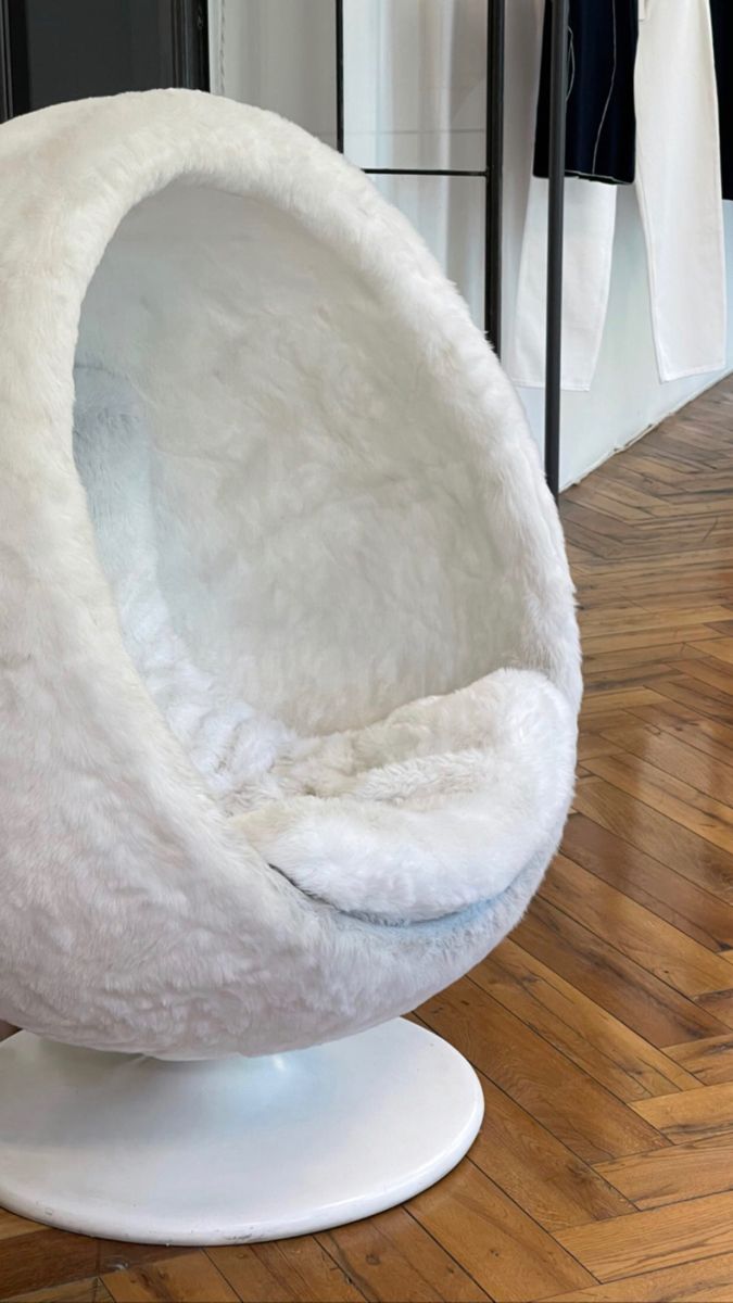 a white egg chair sitting on top of a wooden floor next to a closet door