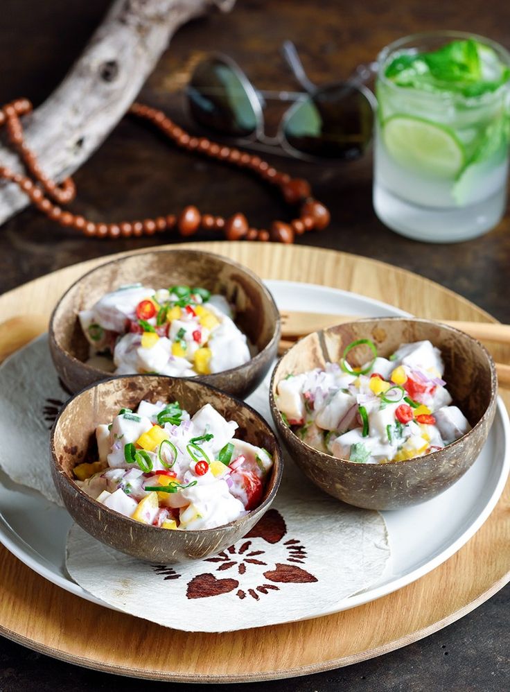 three wooden bowls filled with food sitting on top of a plate next to a drink