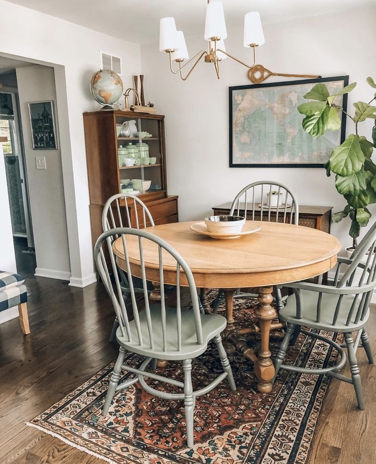 a dining room table with four chairs and a rug on the floor in front of it