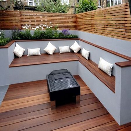 a wooden bench sitting on top of a hard wood floor next to a wall covered in plants