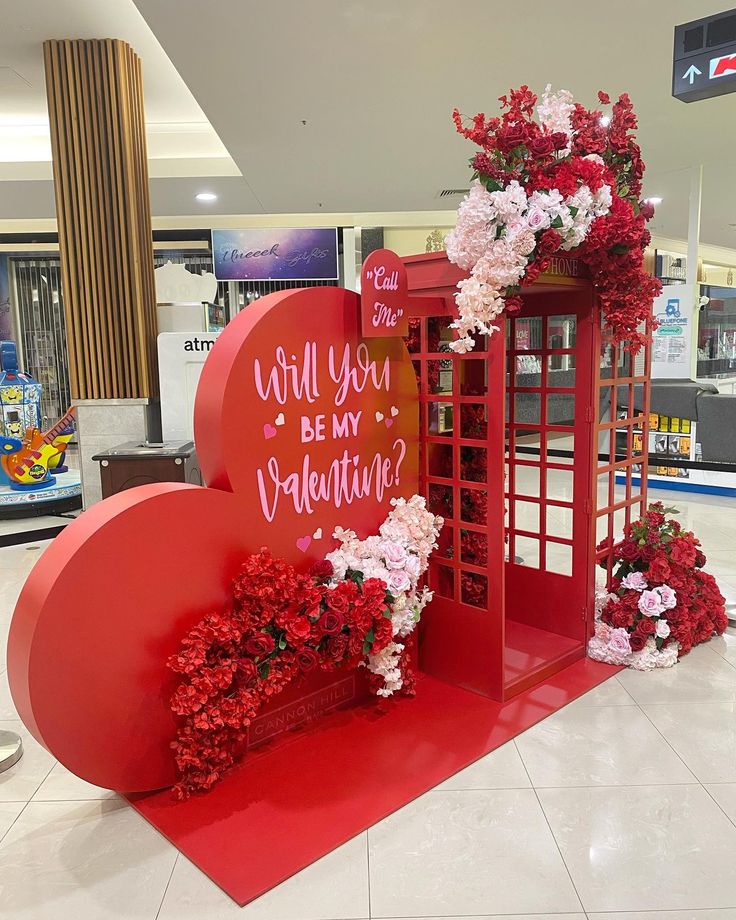 a valentine's day display with flowers and a red phone booth in the background