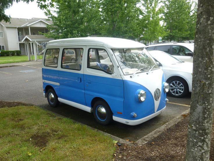 an old blue and white van parked in a parking lot next to another car on the street