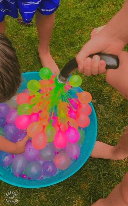 two children playing with balloons in a blue bowl