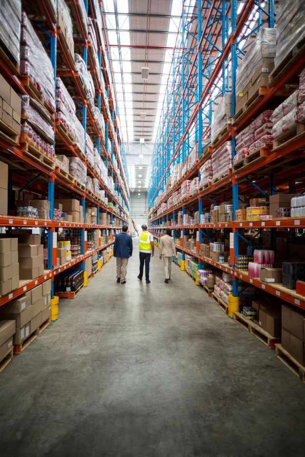 two people walking through a large warehouse filled with shelves