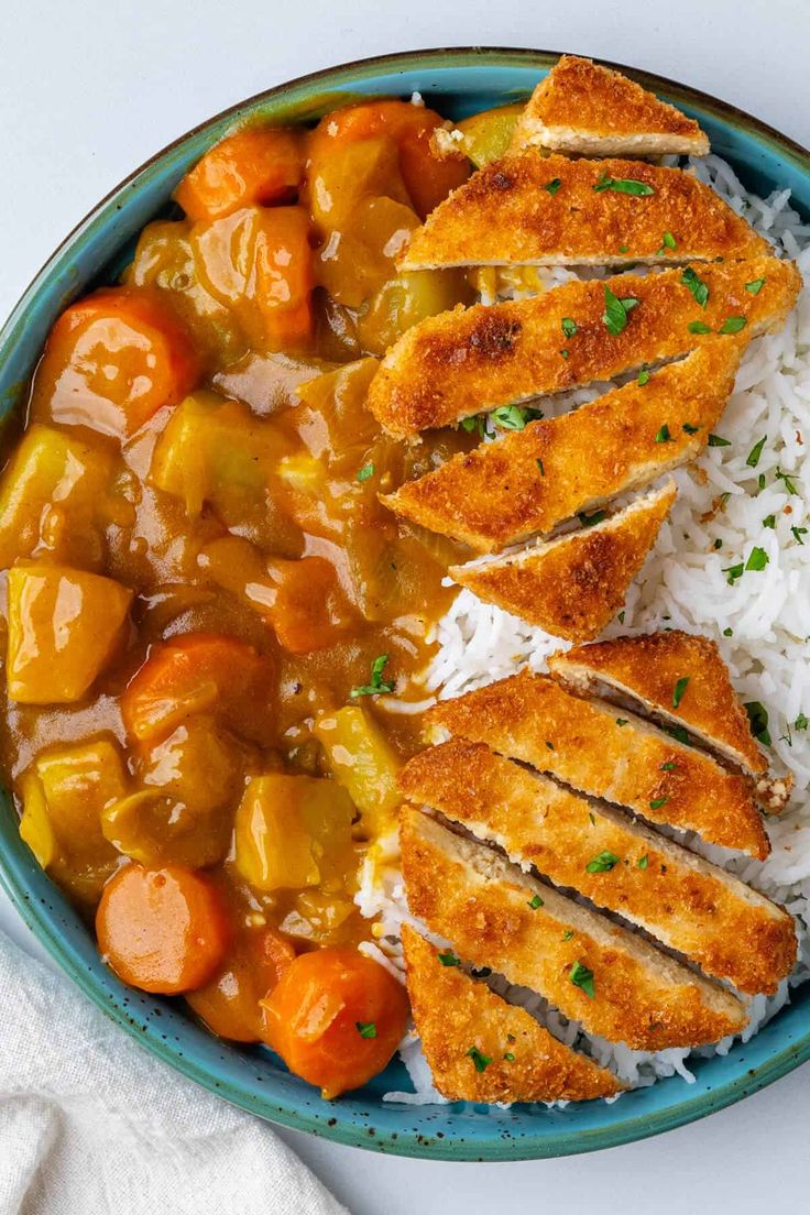 a bowl filled with chicken, rice and carrots on top of a white table