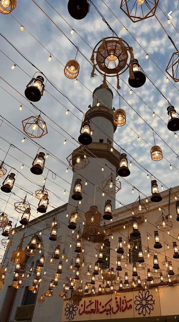 many lights are hanging from the ceiling in front of a building with a clock tower