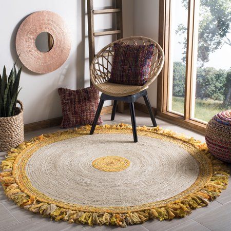 a round rug with yellow fringes on the floor next to a chair and potted plant