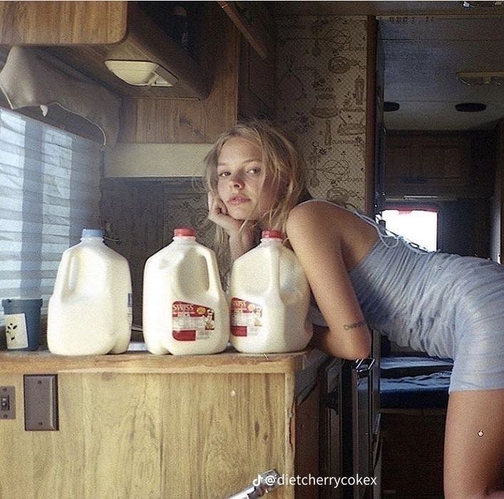 a woman leaning on a counter next to milk bottles