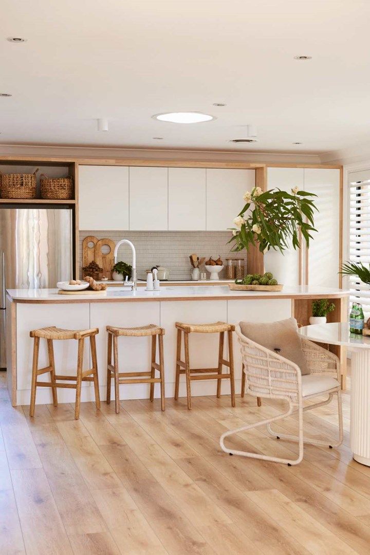 a kitchen with white cabinets and wooden floors is pictured in this image, there are three stools at the center of the island