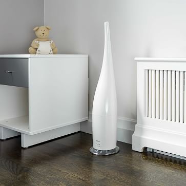 a white vase sitting on top of a wooden floor next to a radiator