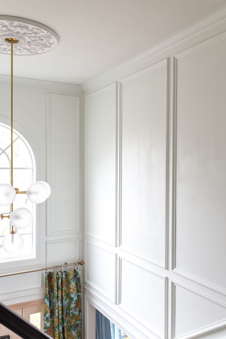 the interior of a house with white walls and wood flooring, including a chandelier