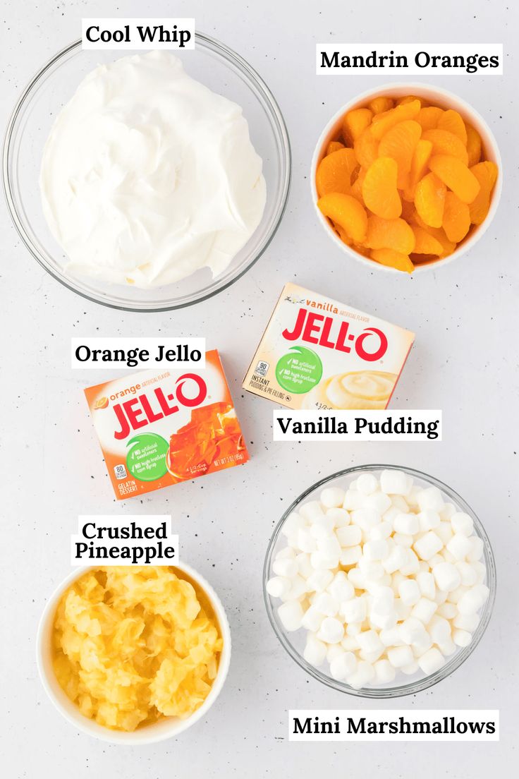 the ingredients to make jello are shown in bowls on a white counter top with oranges, marshmallows, and yogurt