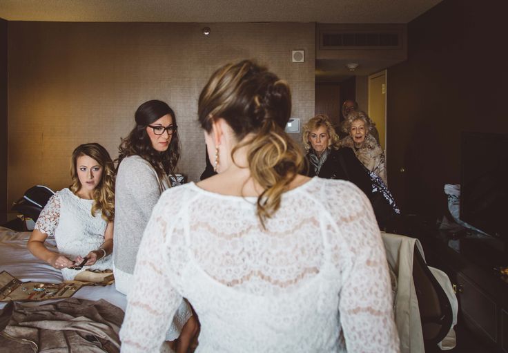 a group of women standing around each other in front of a bed with sheets on it