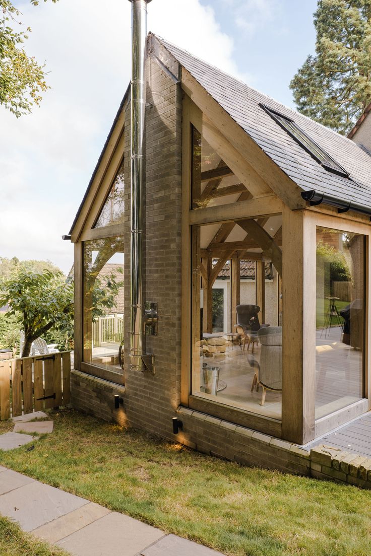 a small wooden house with glass doors on the front and side windows that are open to let in natural light