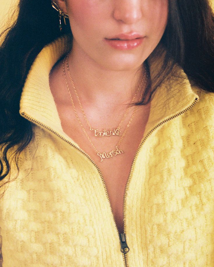 a woman with long hair wearing a yellow jacket and gold earrings, looking at the camera