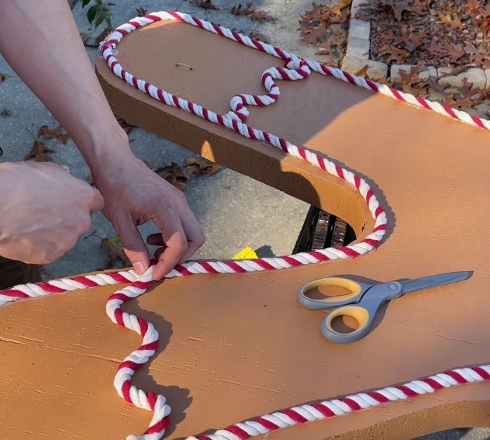 someone is making a chair out of cardboard with scissors and twine around the edge