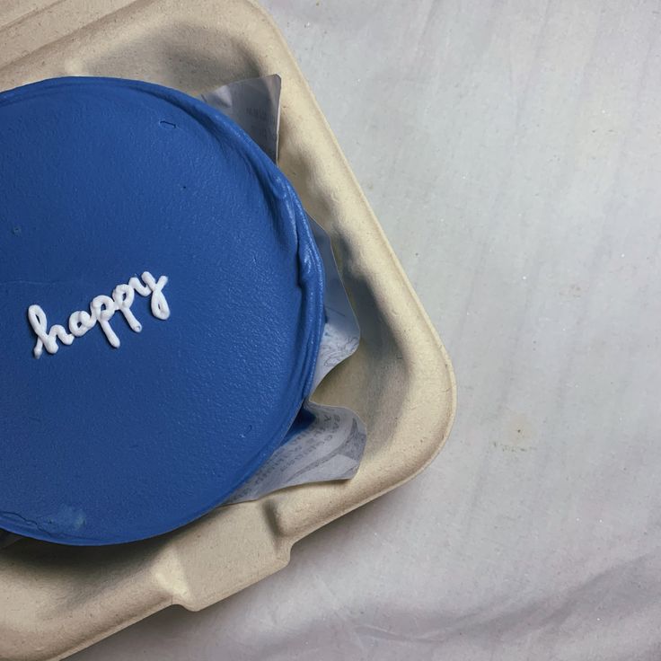 a blue frisbee with the word happy written on it in white letters sits in a foam container