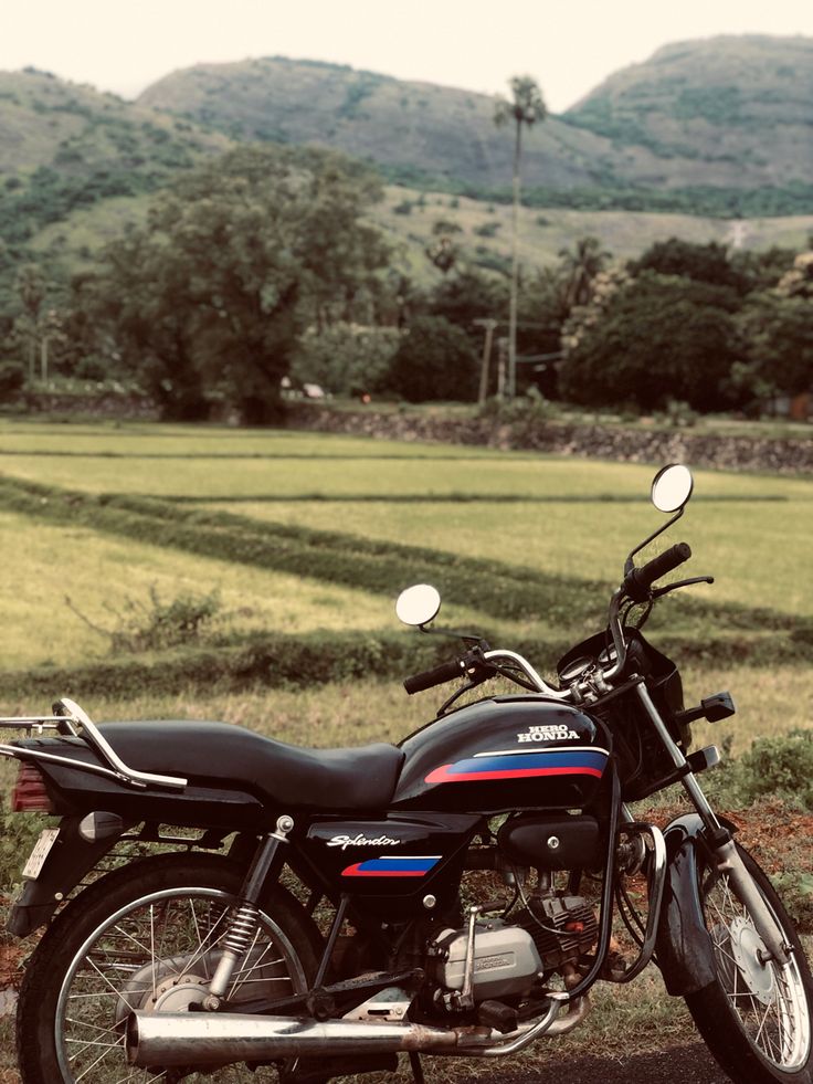 a motorcycle is parked on the side of the road in front of some hills and trees