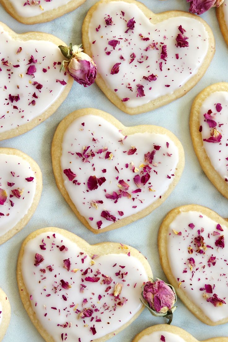 heart shaped cookies decorated with white icing and pink flowers on a blue tablecloth