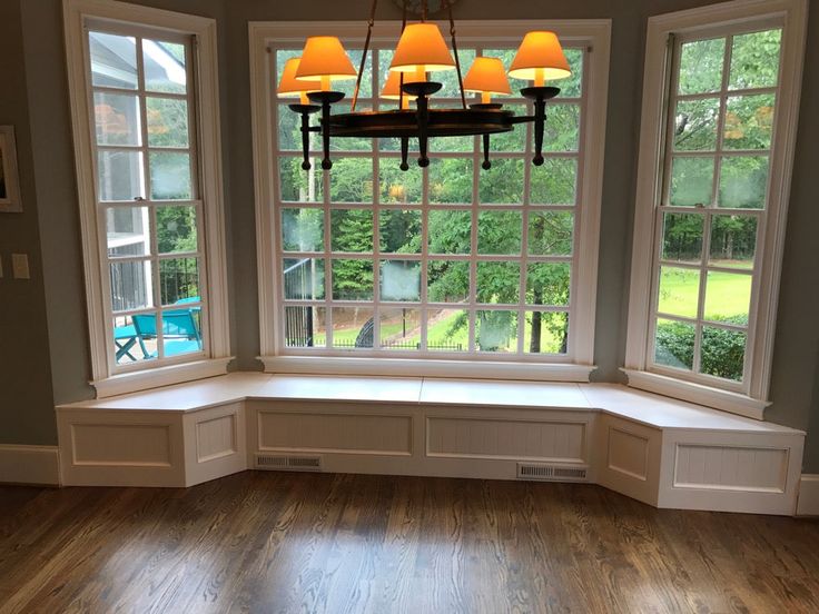 an empty room with three windows and a chandelier