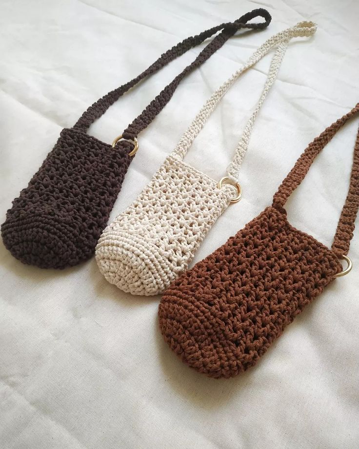 three crocheted purses sitting on top of a white bed next to each other