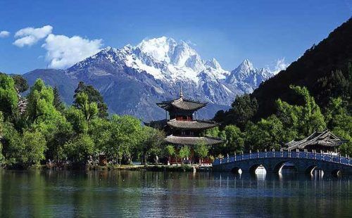 the mountains are covered in snow and there is a bridge that crosses over the water