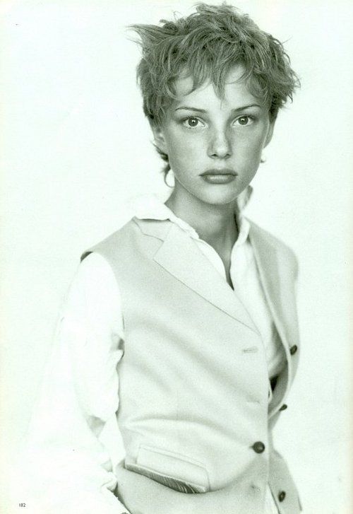 a black and white photo of a woman with short hair wearing a vest over a shirt