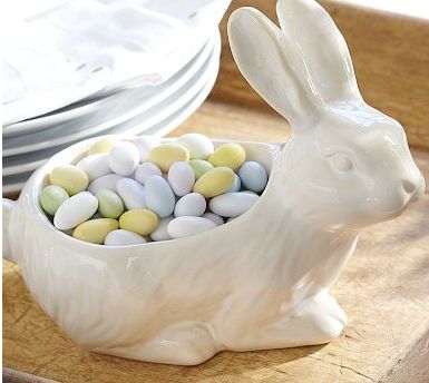 a white bunny sitting in a bowl filled with candy