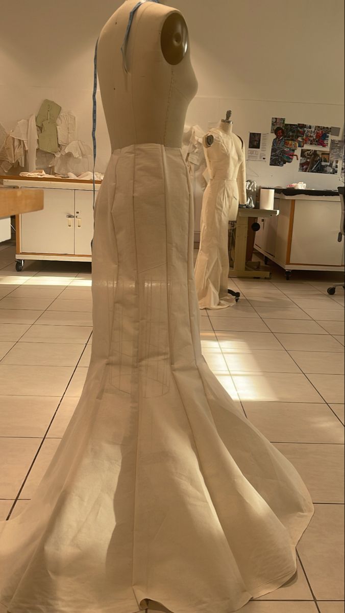 a dress made out of paper on display in a room filled with mannequins