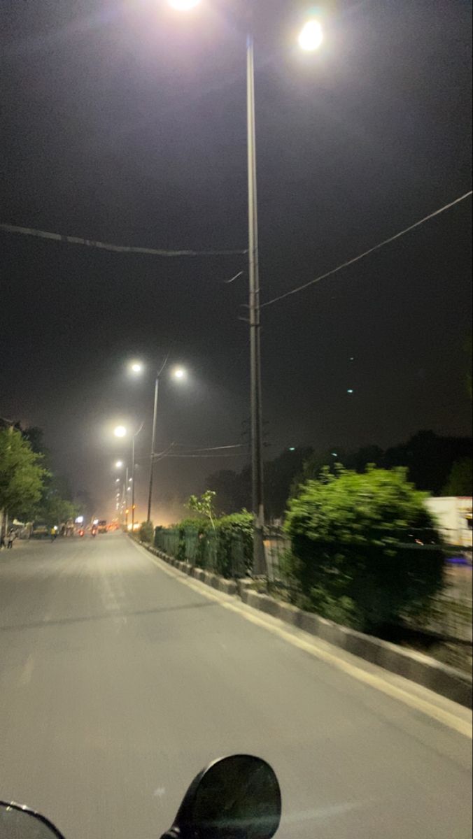 a motorcycle driving down a street at night with bright lights on the top of it