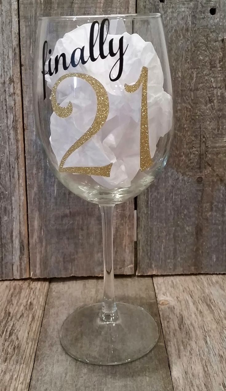 a wine glass with the number twenty one on it and some tissue paper in front of it